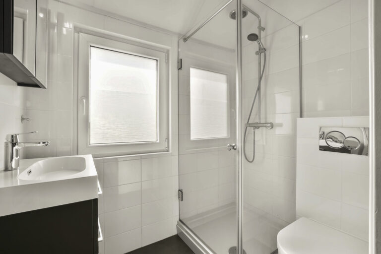 Bathroom with white tiles, shower and ceramic sink in a modern house