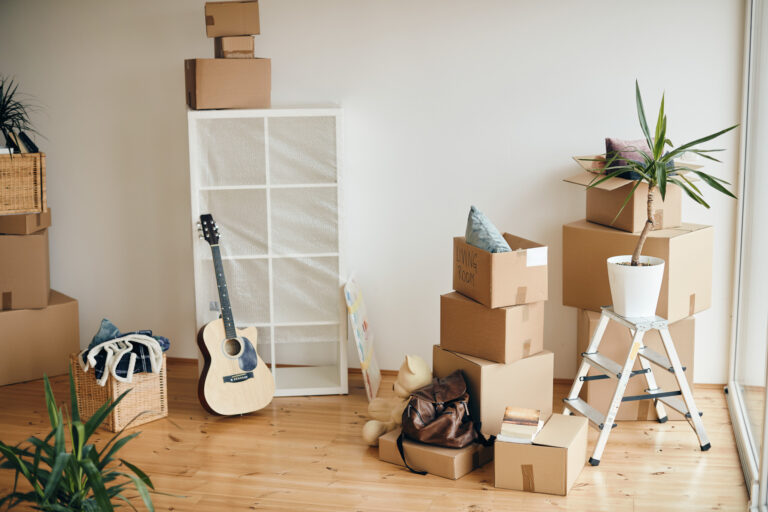 Cardboard boxes and belongings in a living room of a new home.